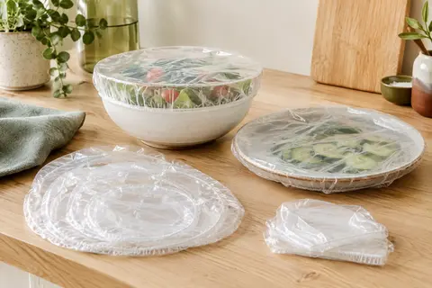 Couvre-plats alimentaires transparents à bord élastique posés sur des bols dans une cuisine claire