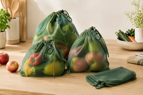 Sacs filet verts en polyester avec cordon, accompagnés de fruits et légumes sur un plan de travail
